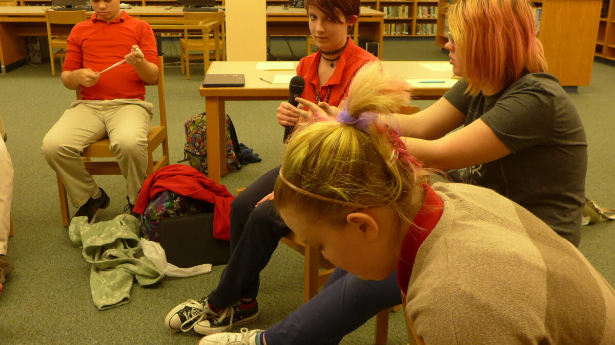 Four teens sitting in a semi-circle in a library