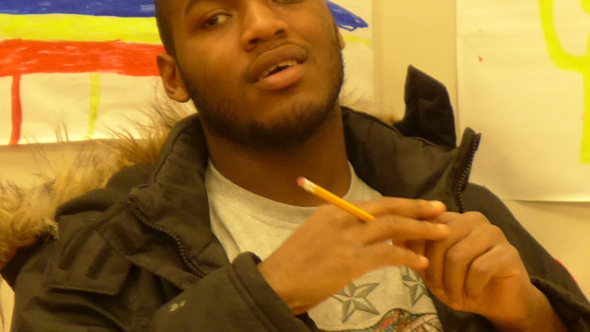 A teen posing while holding a pencil in a classroom