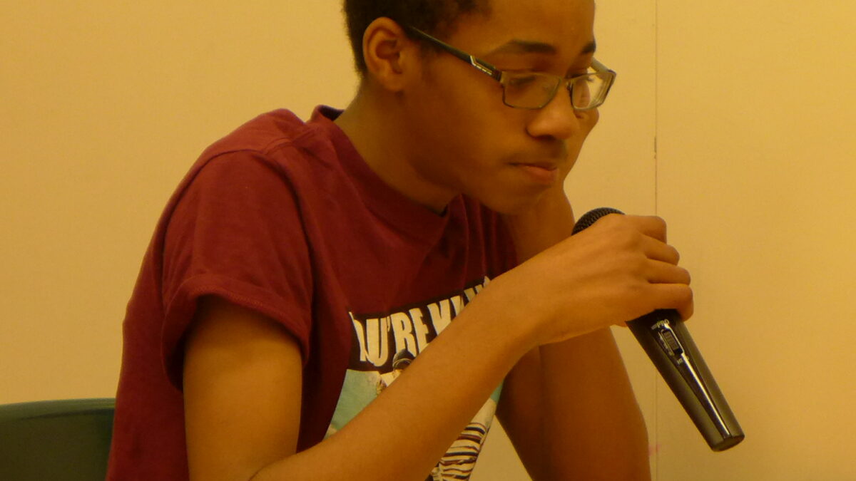 A teen holding a microphone in a classroom