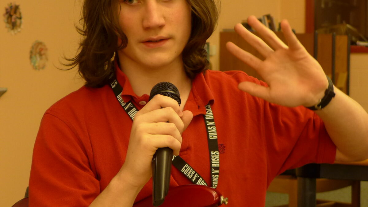 A teen holding a microphone and an electric guitar