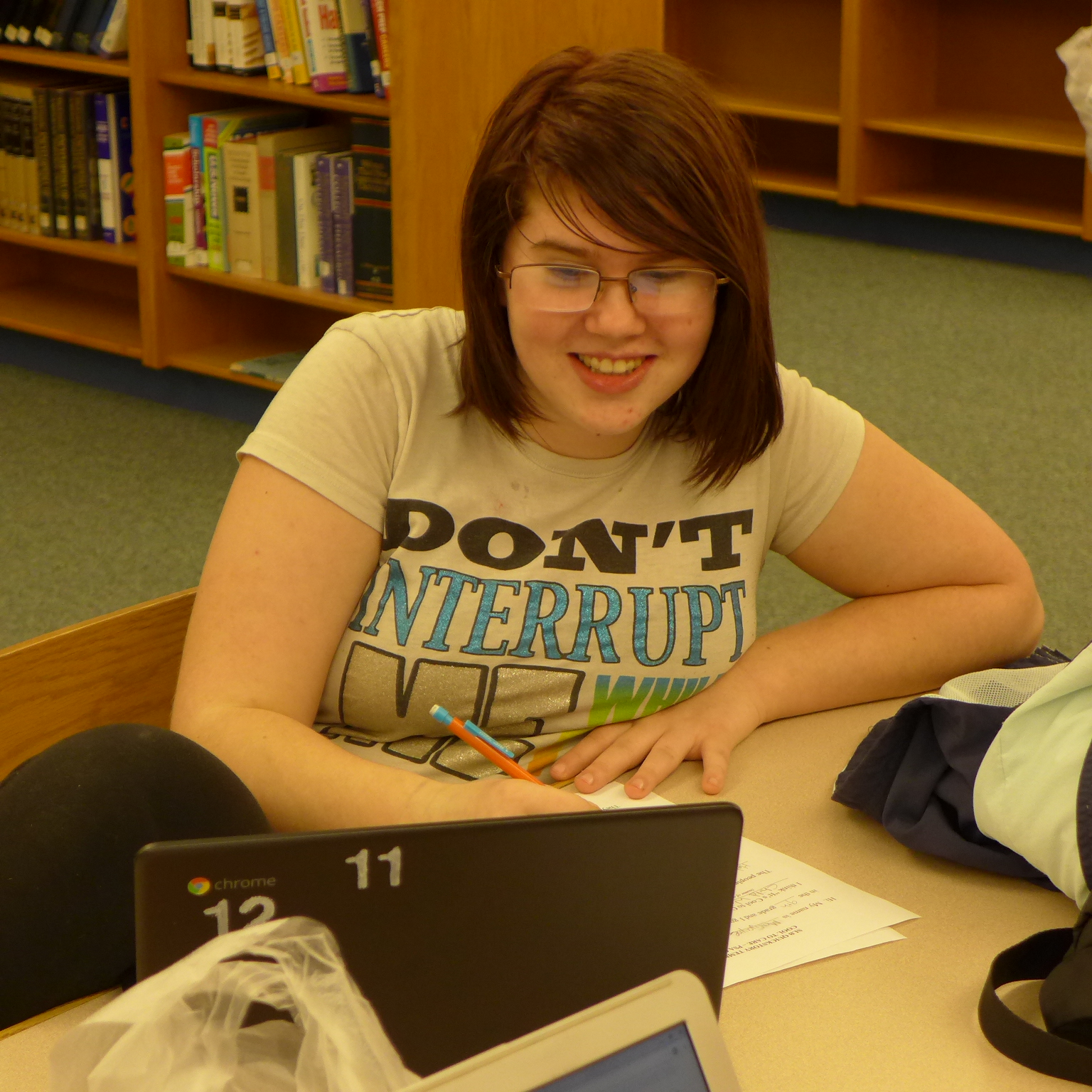 A youth looking at a laptop computer and writing on a piece of paper