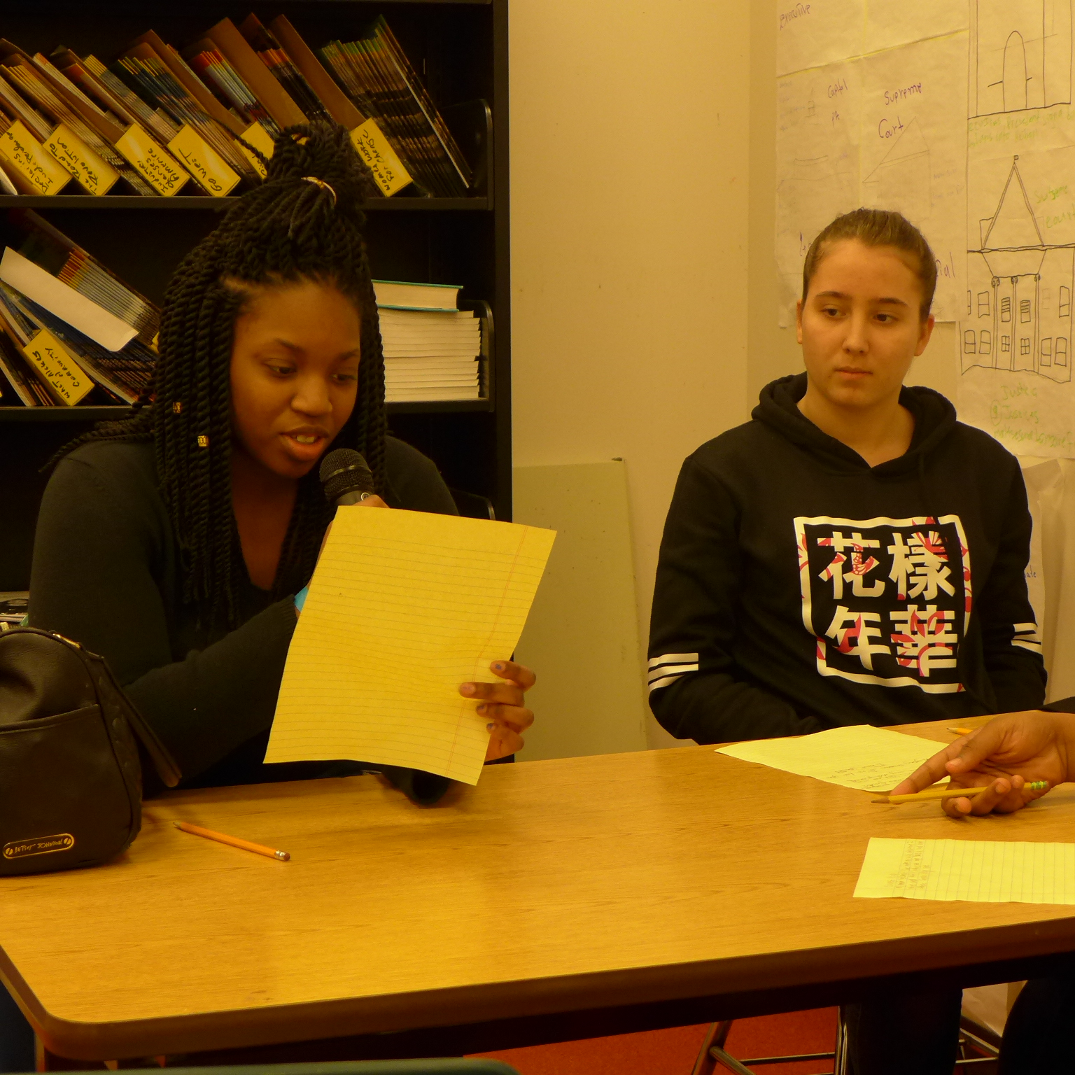 Two youth looking at a piece of paper in a classroom
