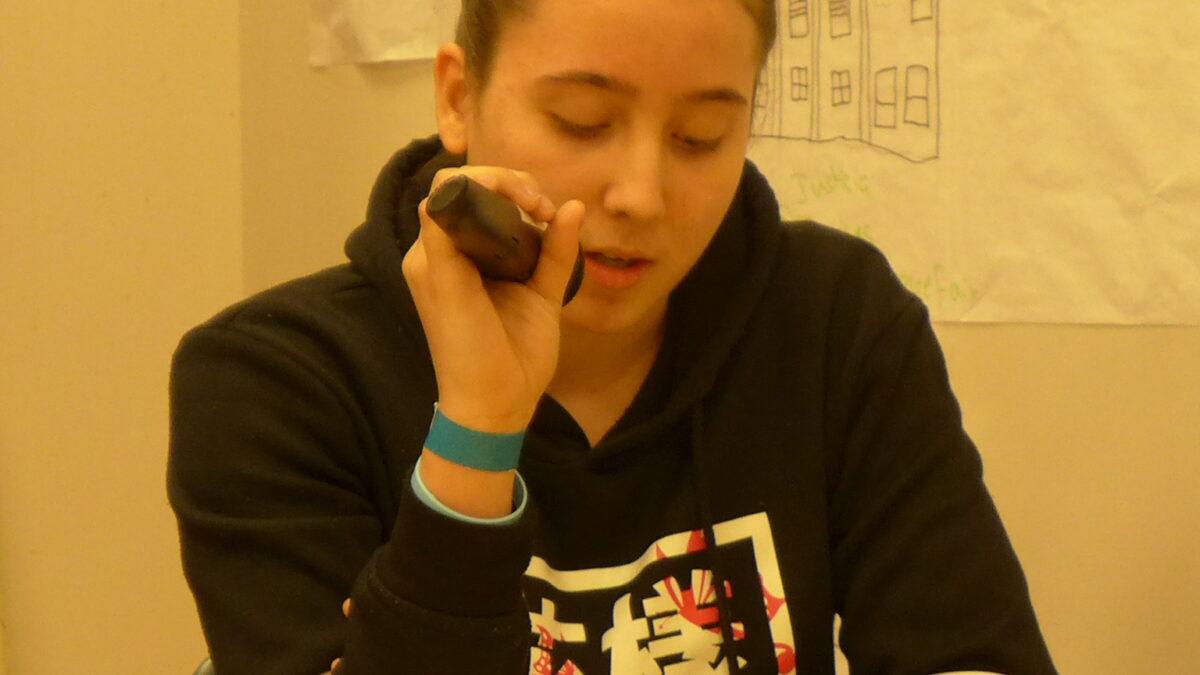 A teen speaking into a microphone in a classroom