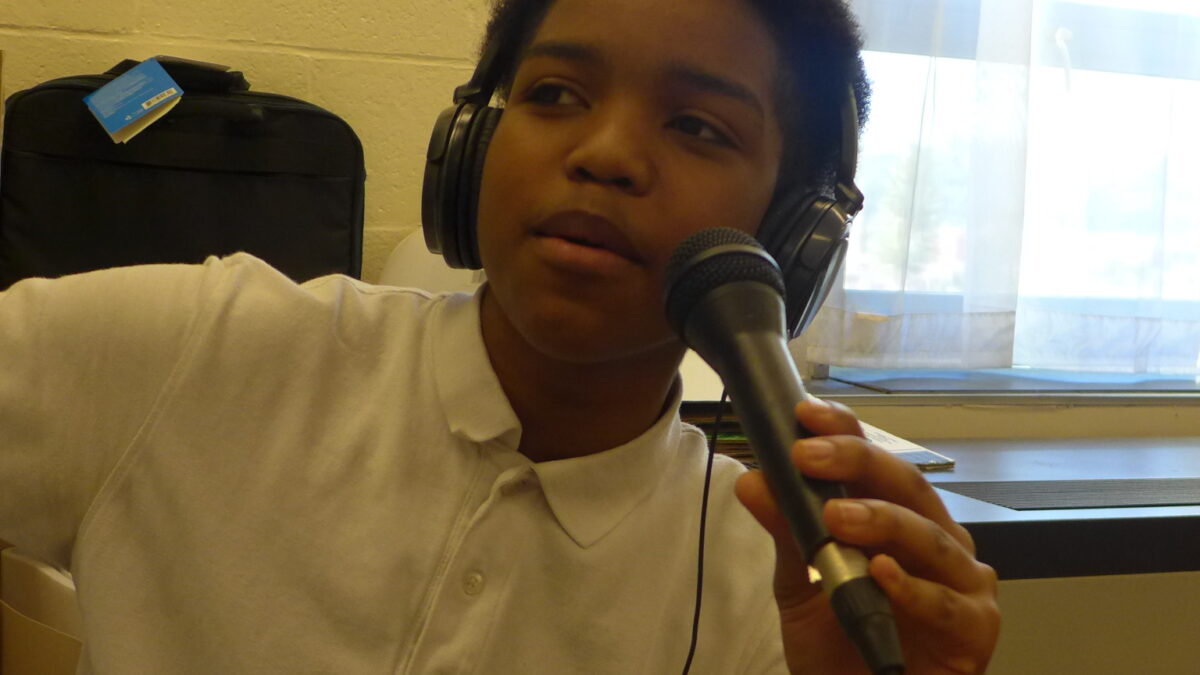 A youth wearing headphones speaking into a microphone