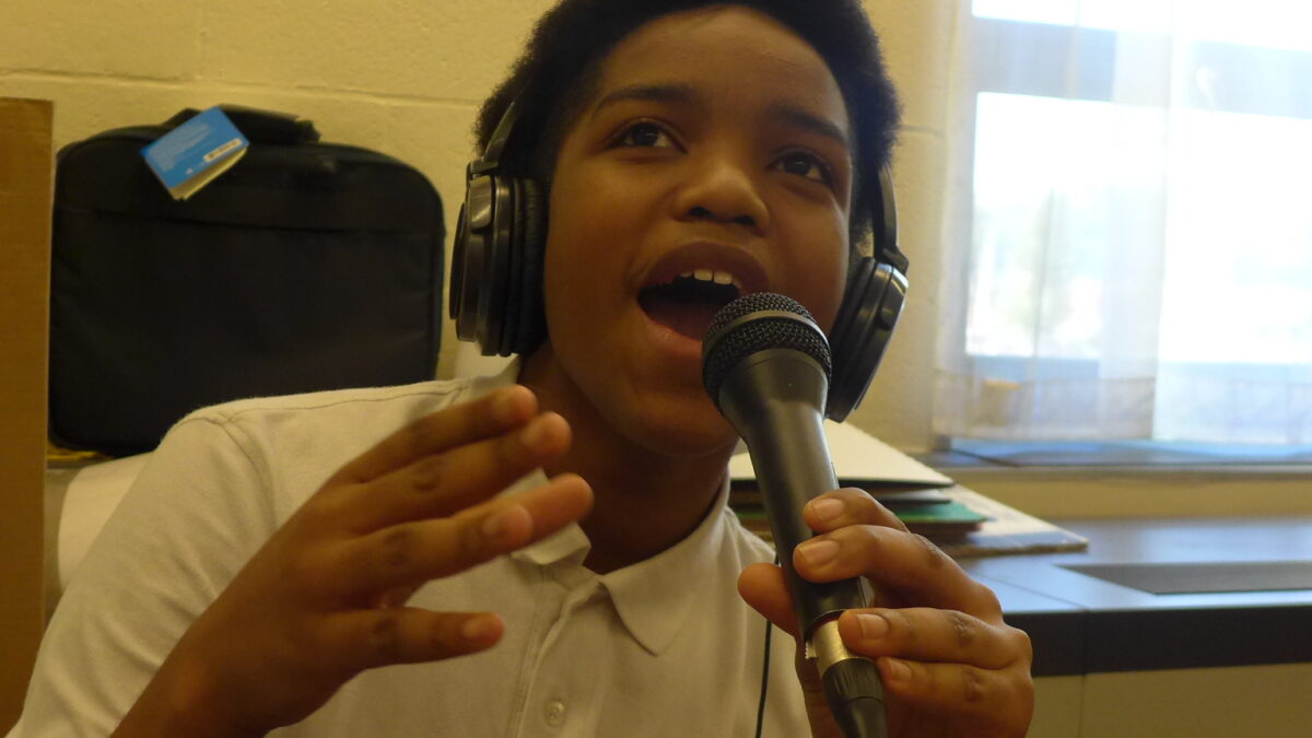 A youth wearing headphones speaking into a microphone