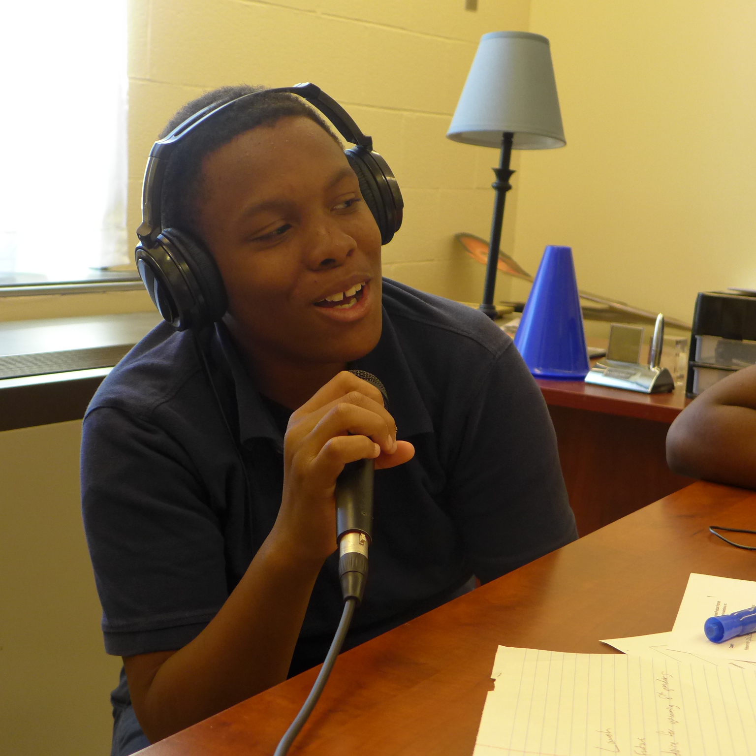 A youth wearing headphones speaking into a microphone