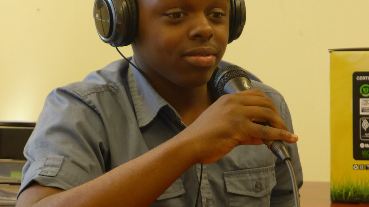 A youth wearing headphones speaking into a microphone