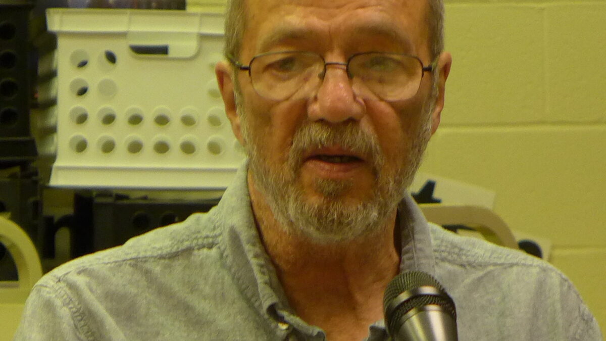 An adult speaking into a microphone in a classroom