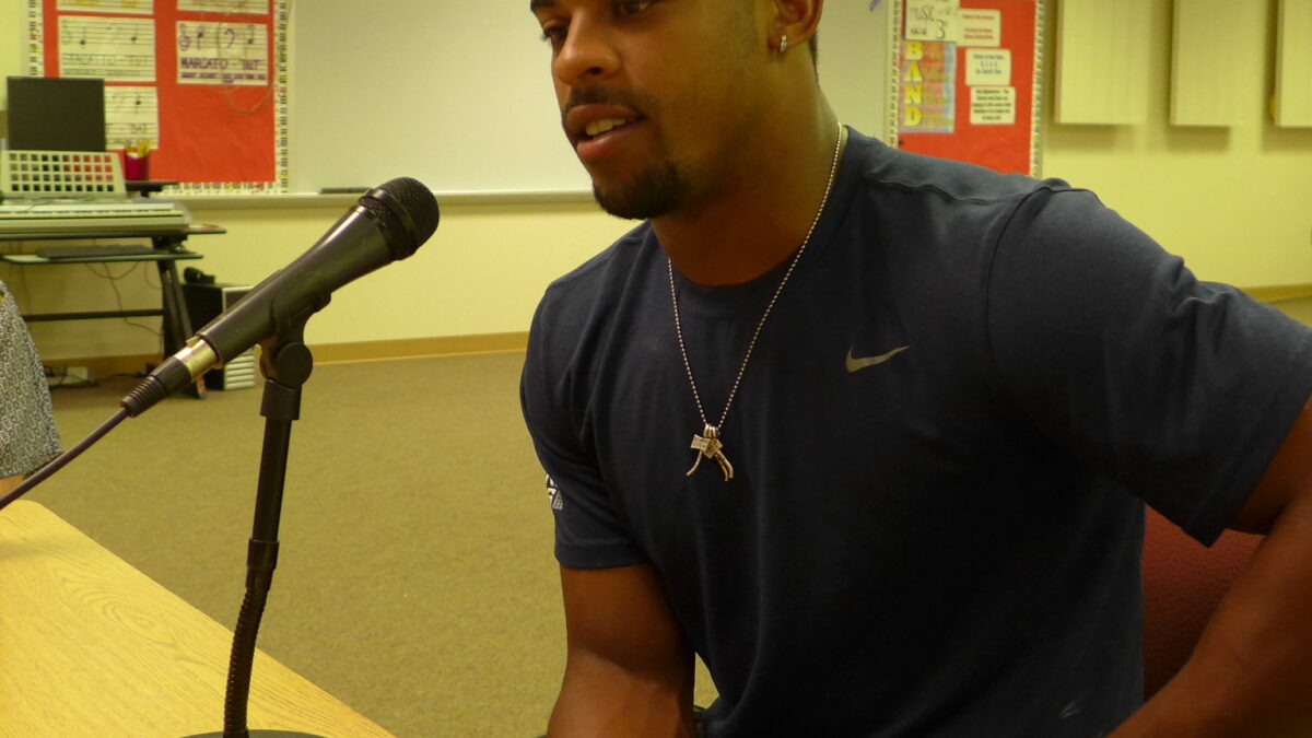An adult speaking into a microphone in a classroom