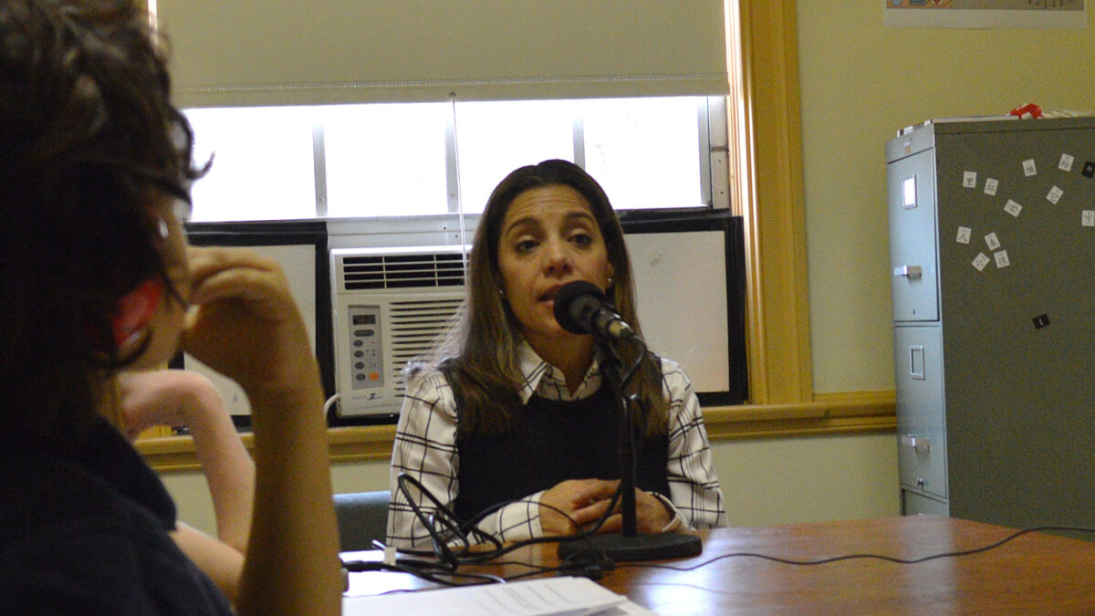 A youth wearing headphones interviewing an adult speaking into a microphone in a library