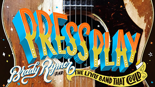 An acoustic guitar with the text "Press Play" in orange and yellow gradient font, "Brady Rymer" in cursive white font, and "and the Little Band that Could" in black font on a yellow ribbon