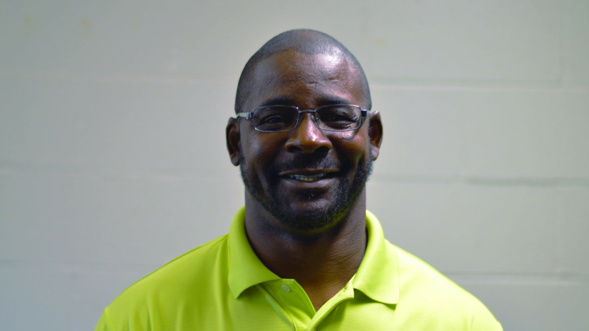 An adult wearing a yellow shirt smiling in profile