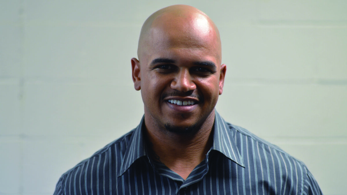 An adult wearing a dark gray shirt smiling in profile