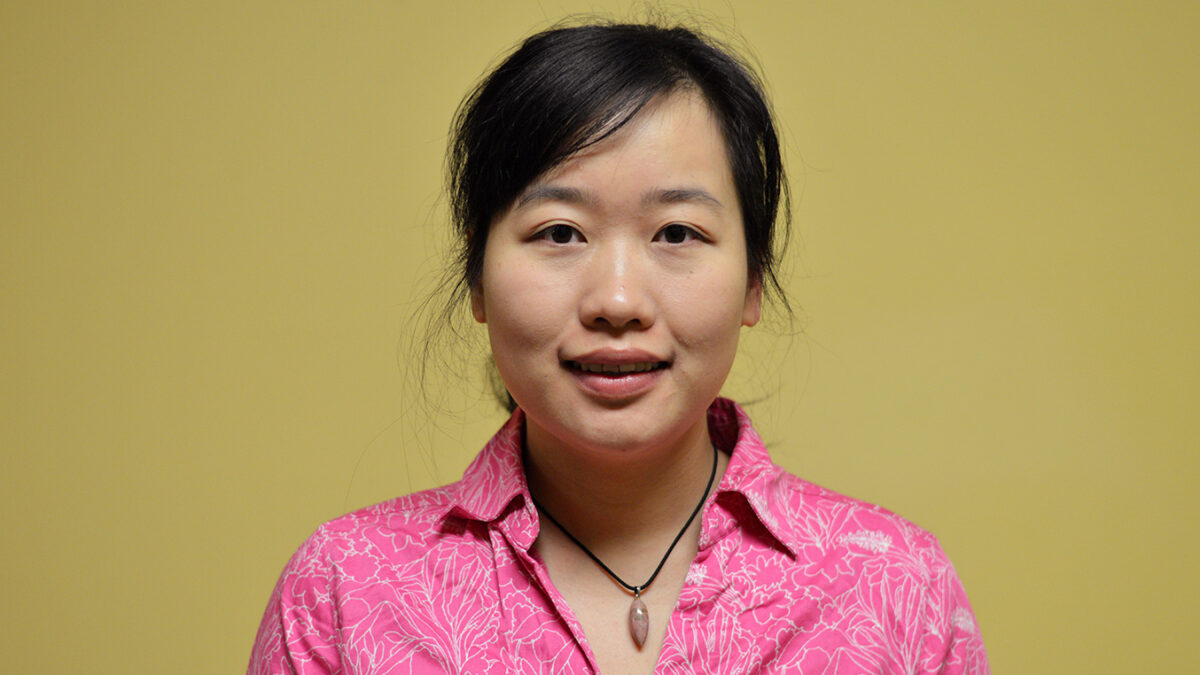 An adult wearing a pink top posing in profile