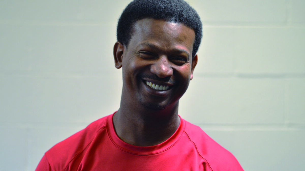 An adult wearing a red shirt smiling in profile