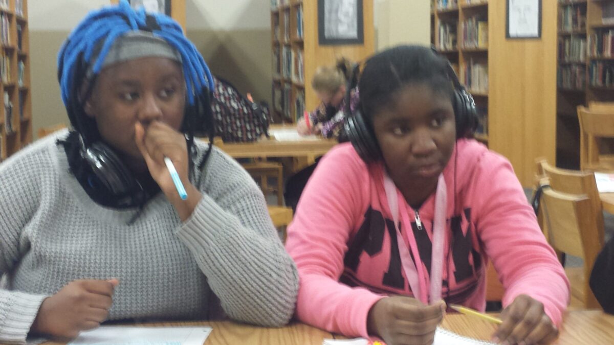 20151215_161927 Two teens wearing headphones sitting at a wooden table in a library