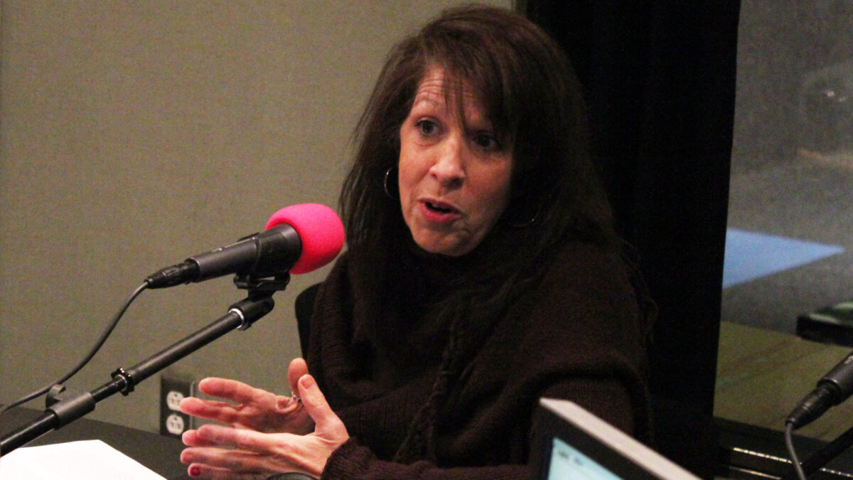 An adult speaking into a microphone in a radio studio