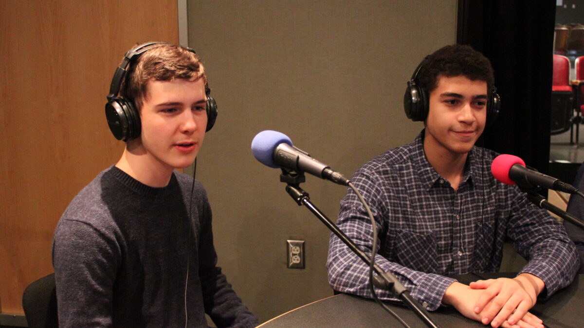 IMG_0554 Two teens wearing headphones speaking into microphones in a radio studio