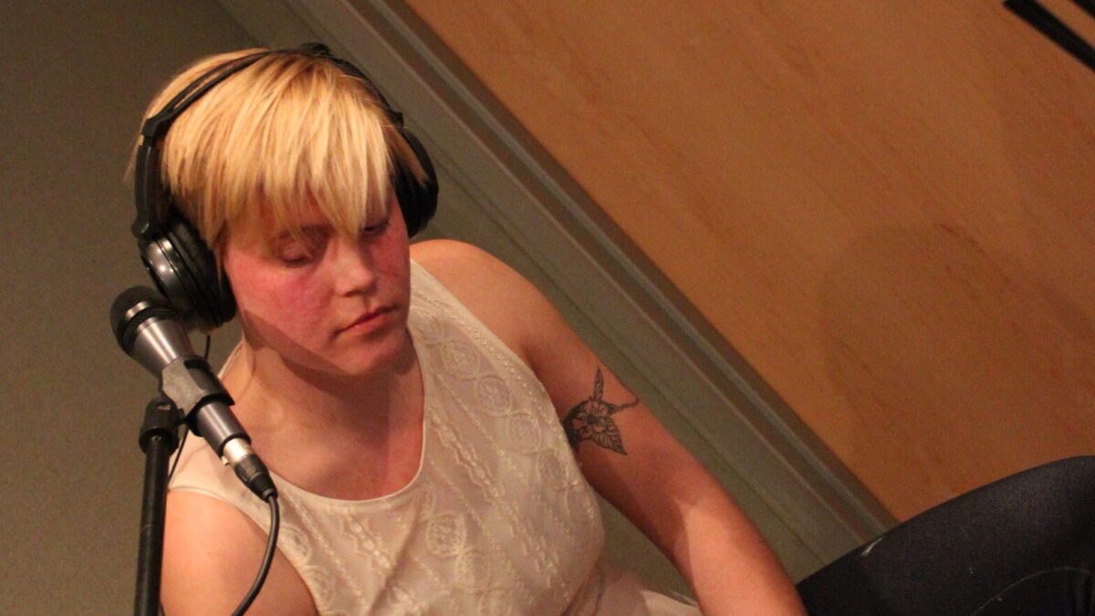 IMG_0638 An adult wearing headphones playing a cajon in a radio studio