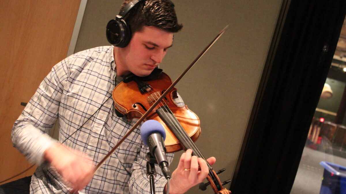 IMG_0639 An adult wearing headphones playing a violin in a radio studio