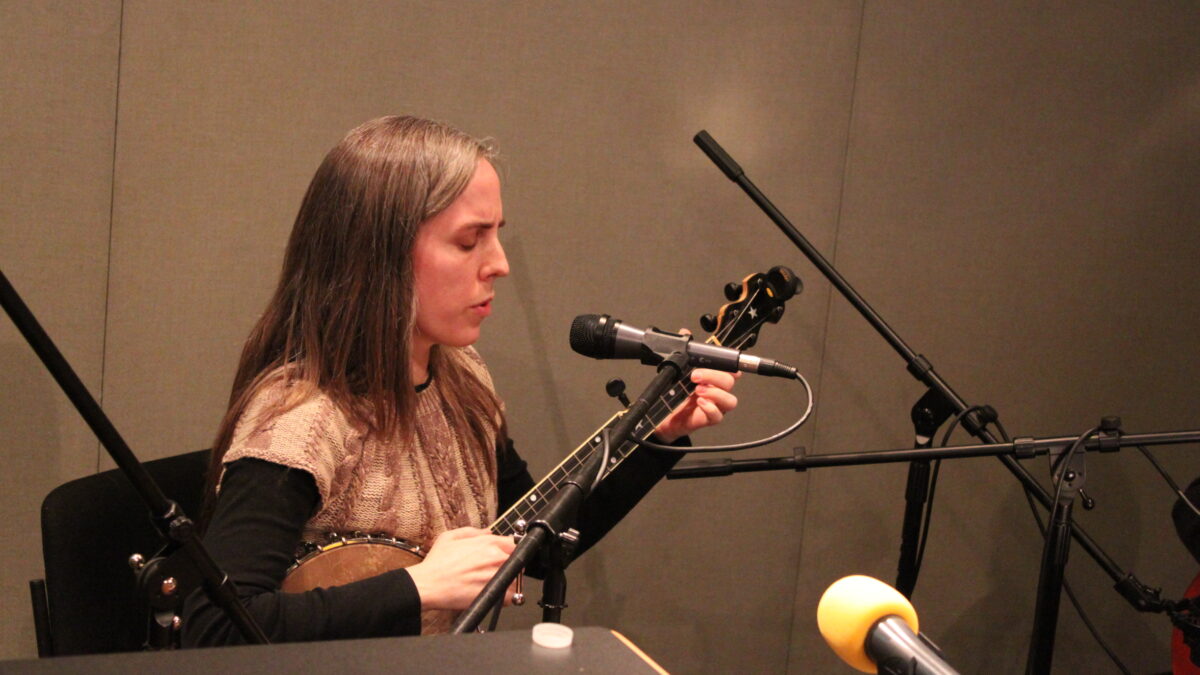 IMG_0838 An adult playing a banjo and singing into a microphone in a radio studio