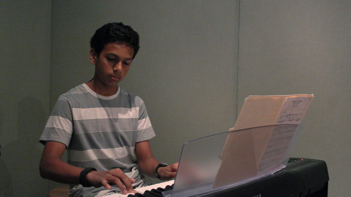 A youth playing a piano keyboard in a radio studio