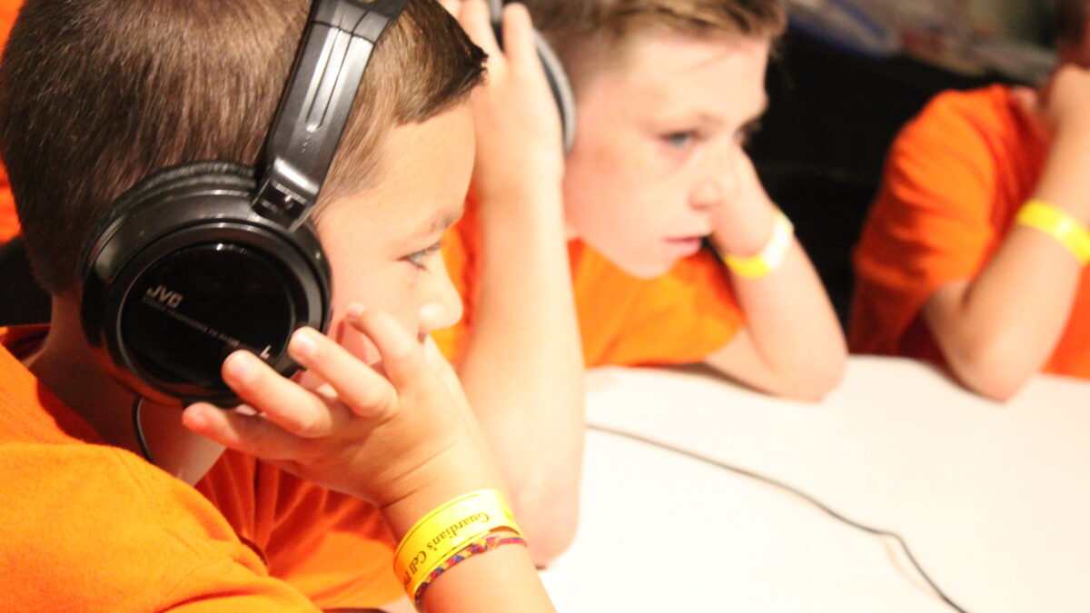 Two youth wearing headphones sitting at a white table