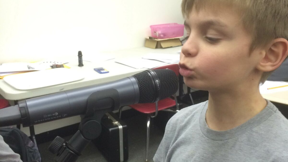 A youth speaking into a microphone in a classroom