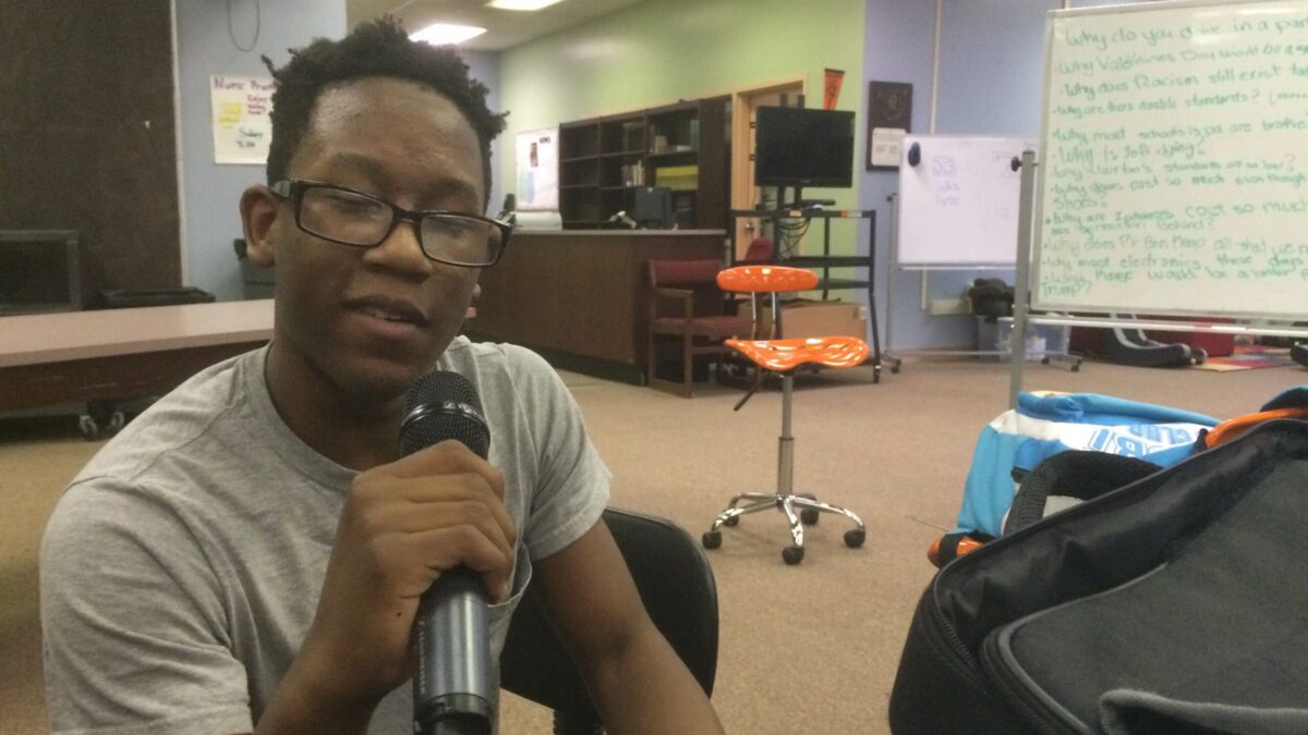 A youth speaking into a microphone in a classroom