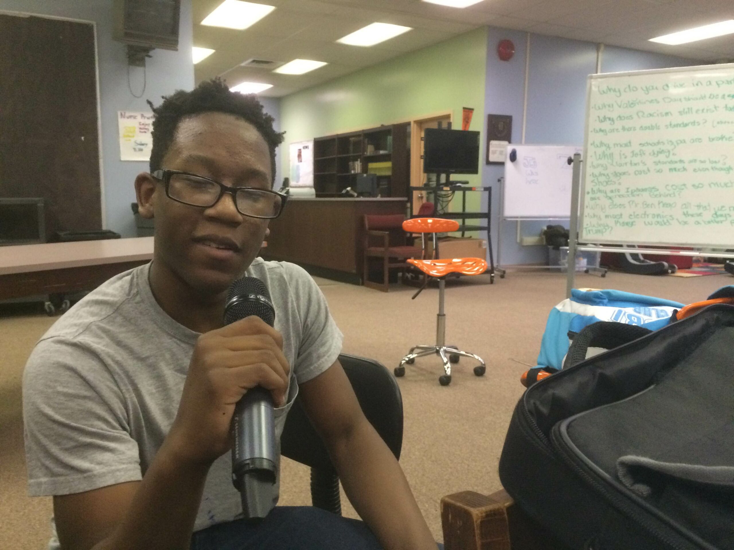 A youth speaking into a microphone in a classroom