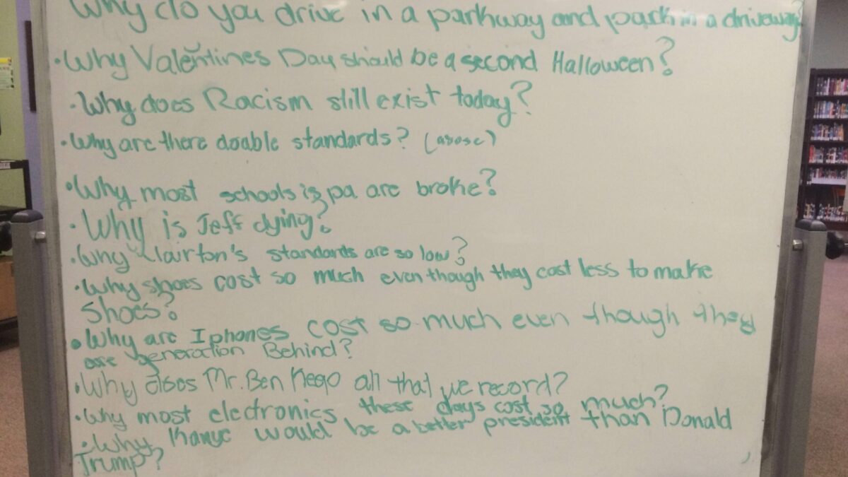 A whiteboard covered in questions written in light green marker