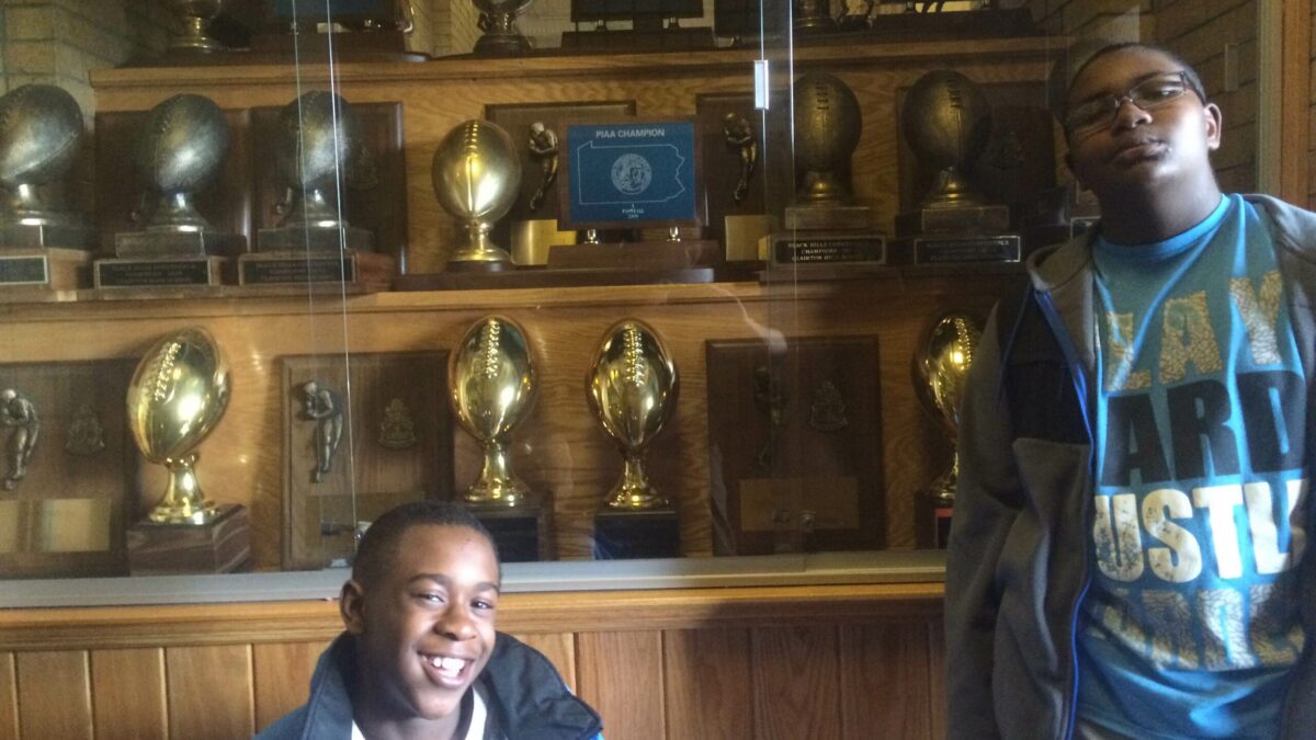 Two youth posing in front of a trophy case