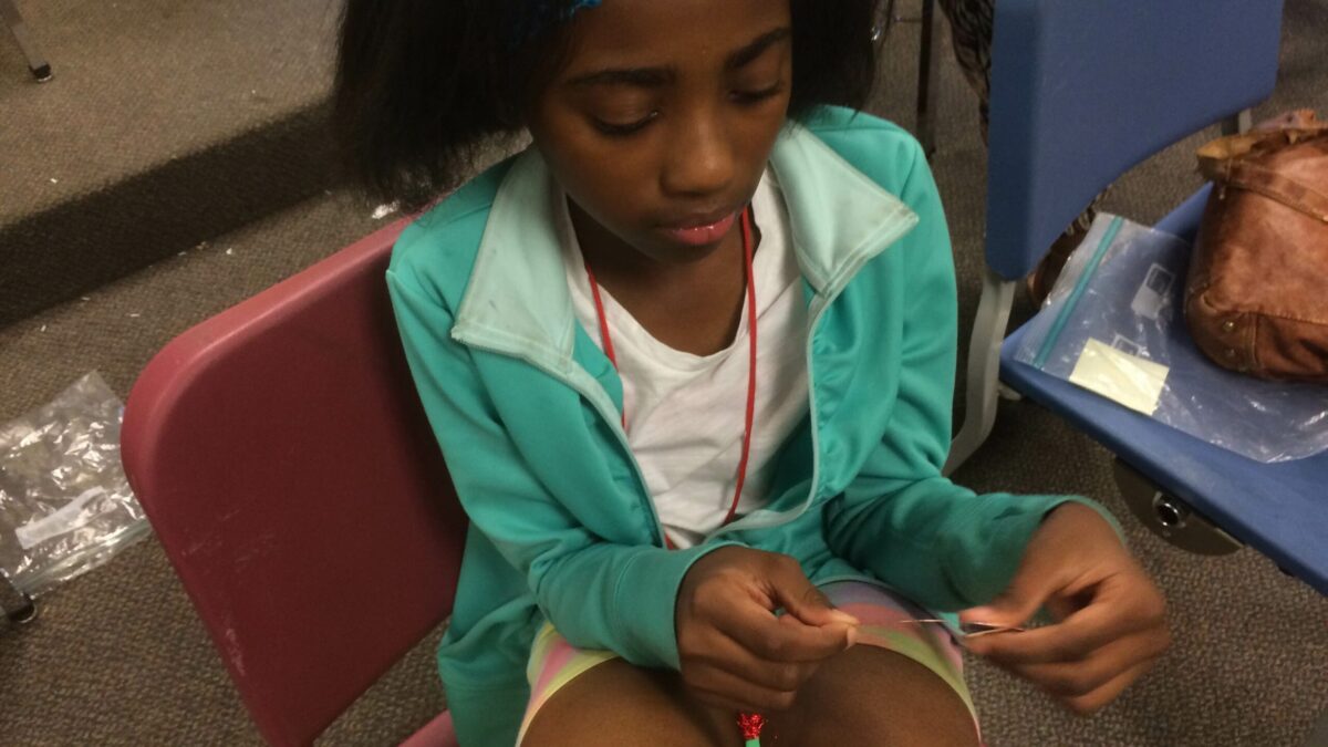 A youth sitting while holding a piece of string