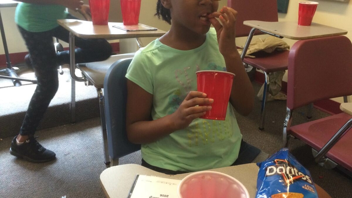 A youth eating a chip and holding a red solo cup