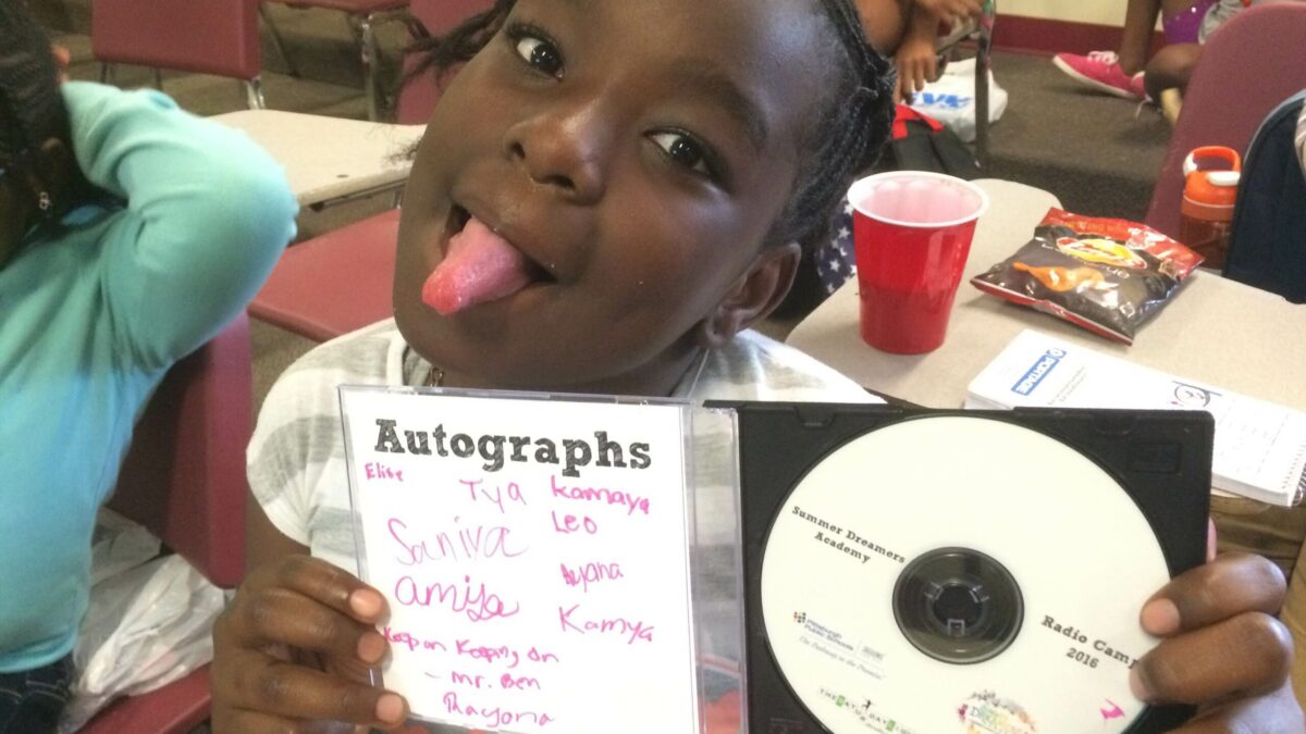 A youth sticking out their tongue while holding an open CD case