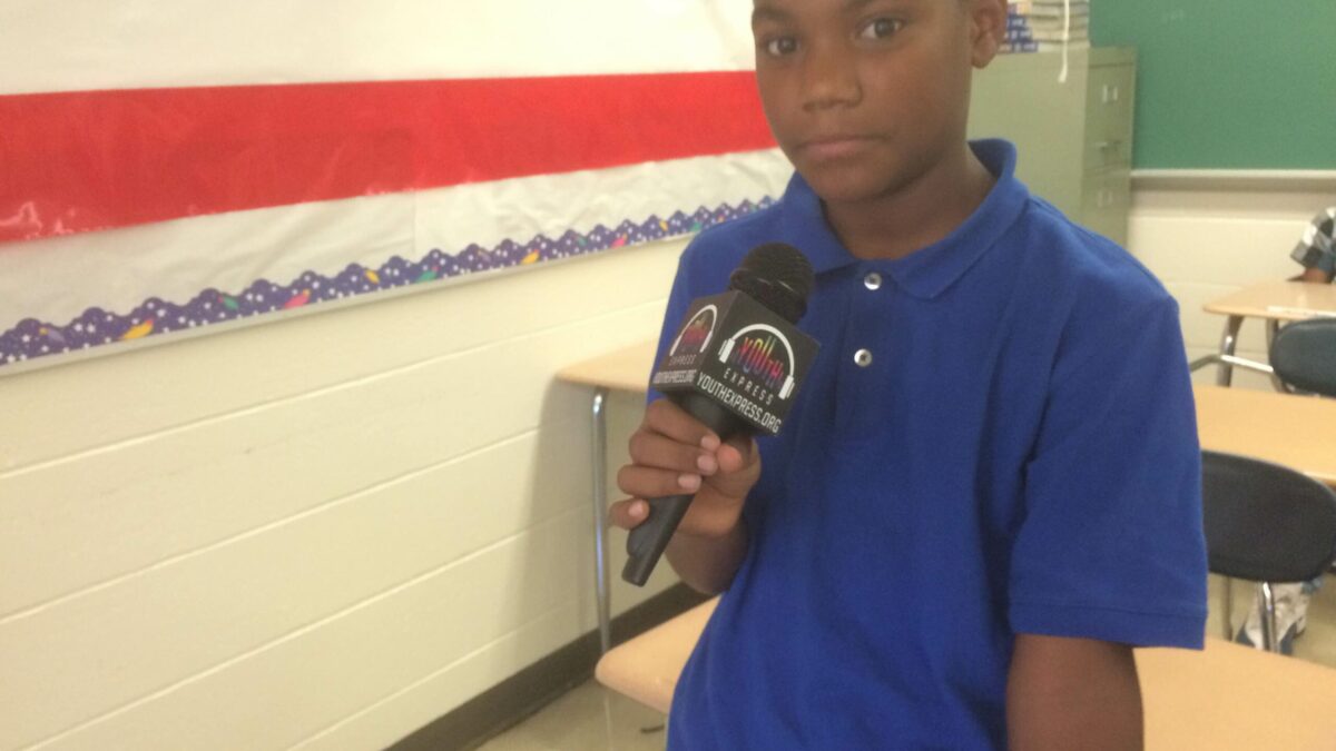 A youth holding a microphone in a classroom.