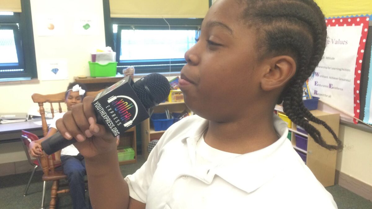 A youth holding a microphone in a classroom