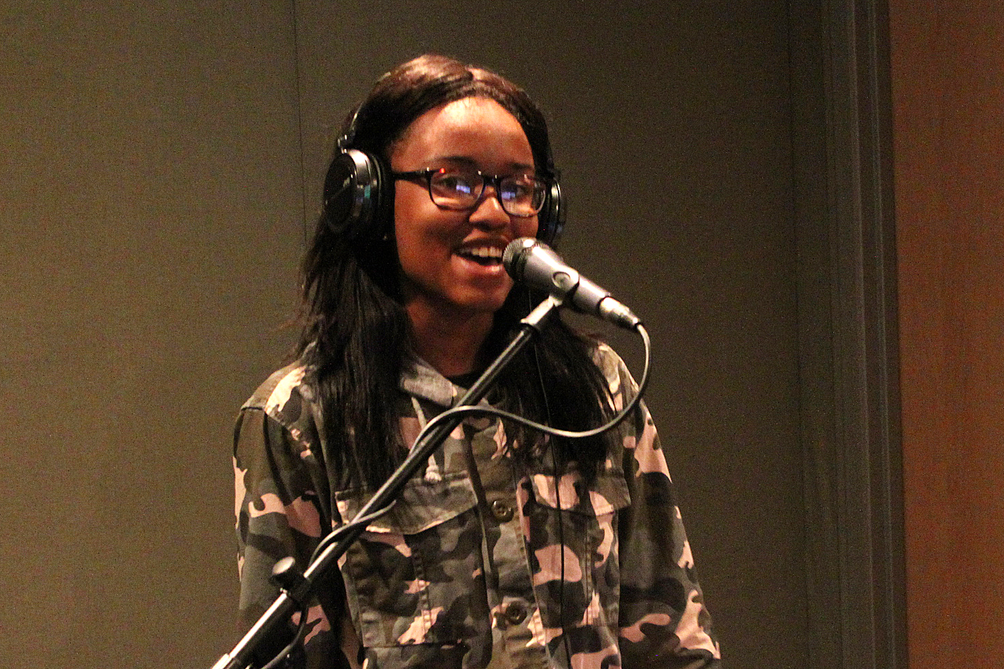A teen singing into a microphone in a radio studio