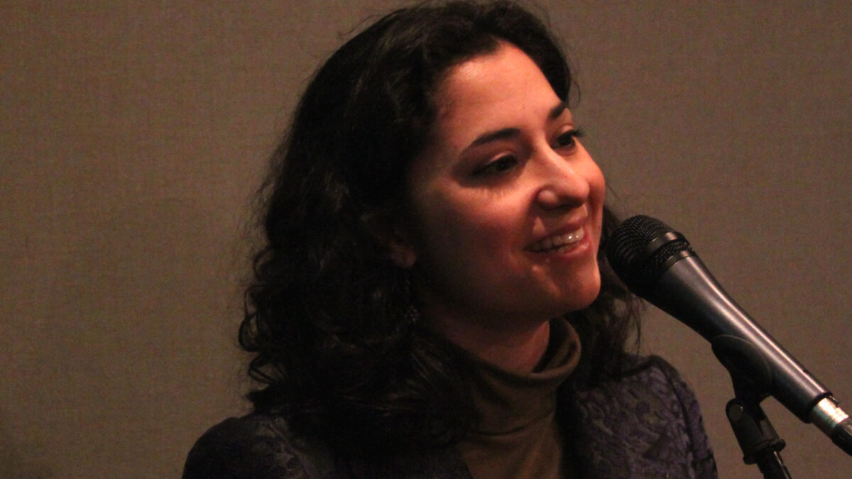 An adult singing into a microphone in a radio studio