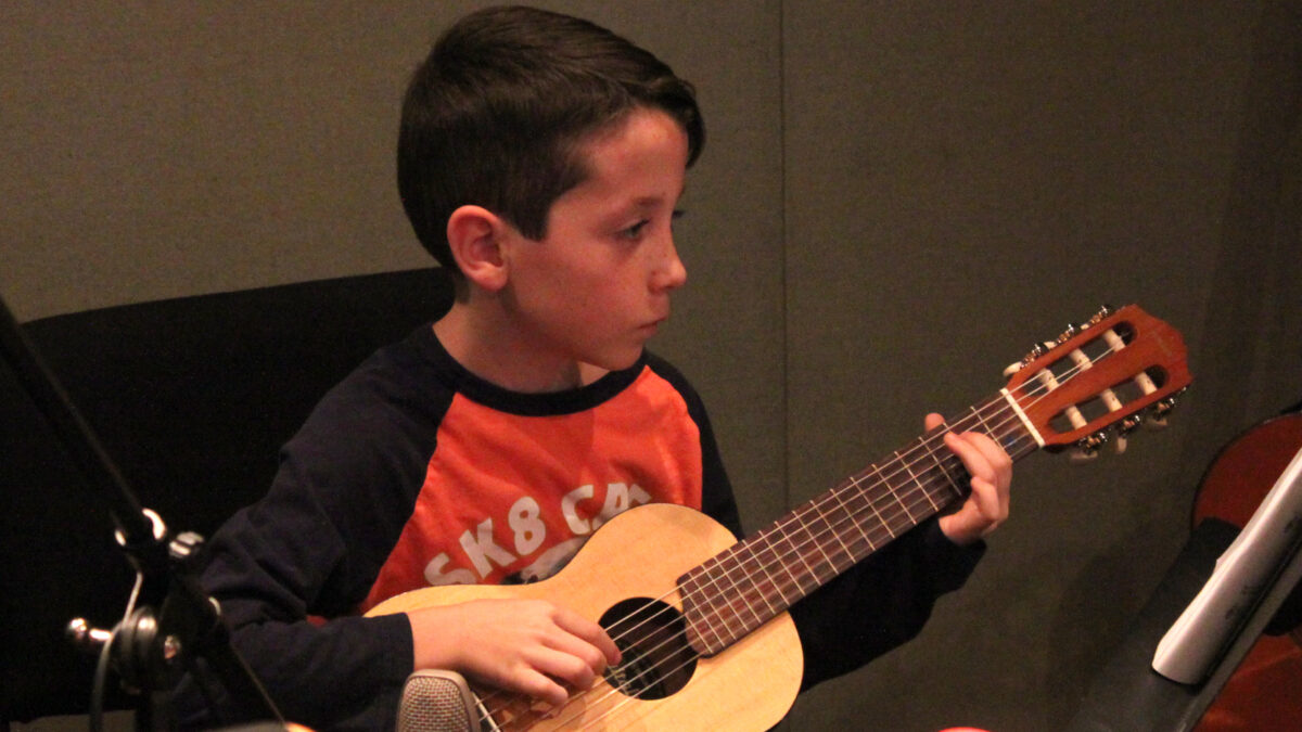 IMG_5012 A youth playing a small acoustic guitar in a radio studio