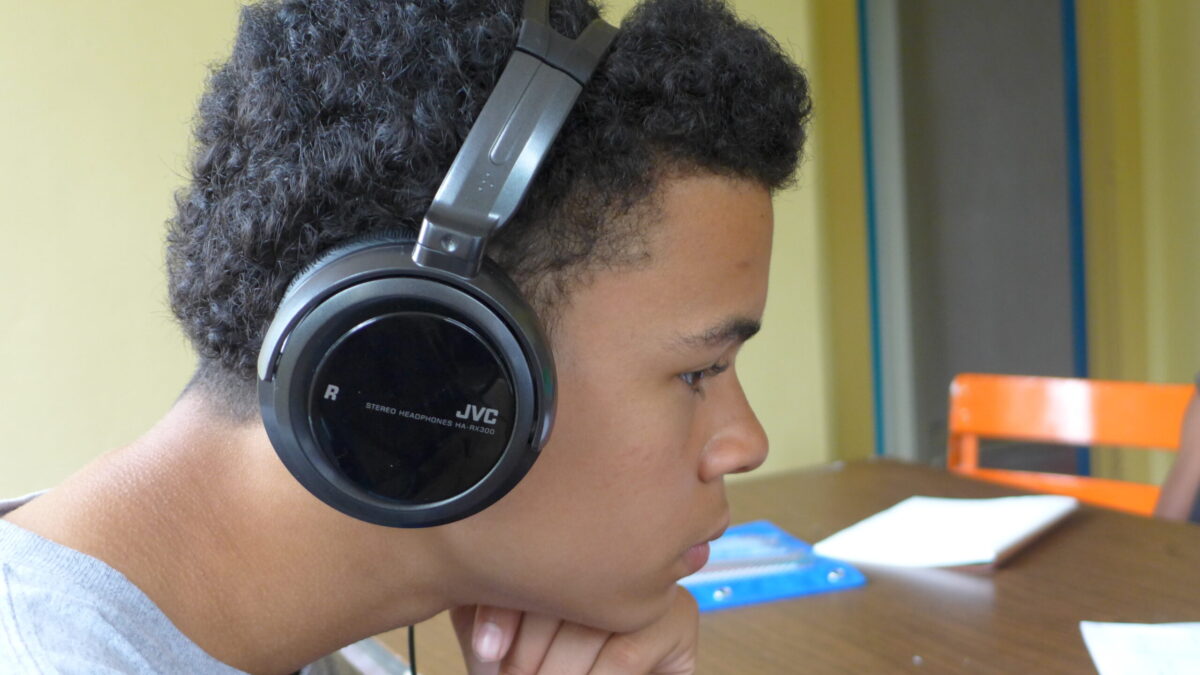 A youth wearing headphones putting their chin on their fist