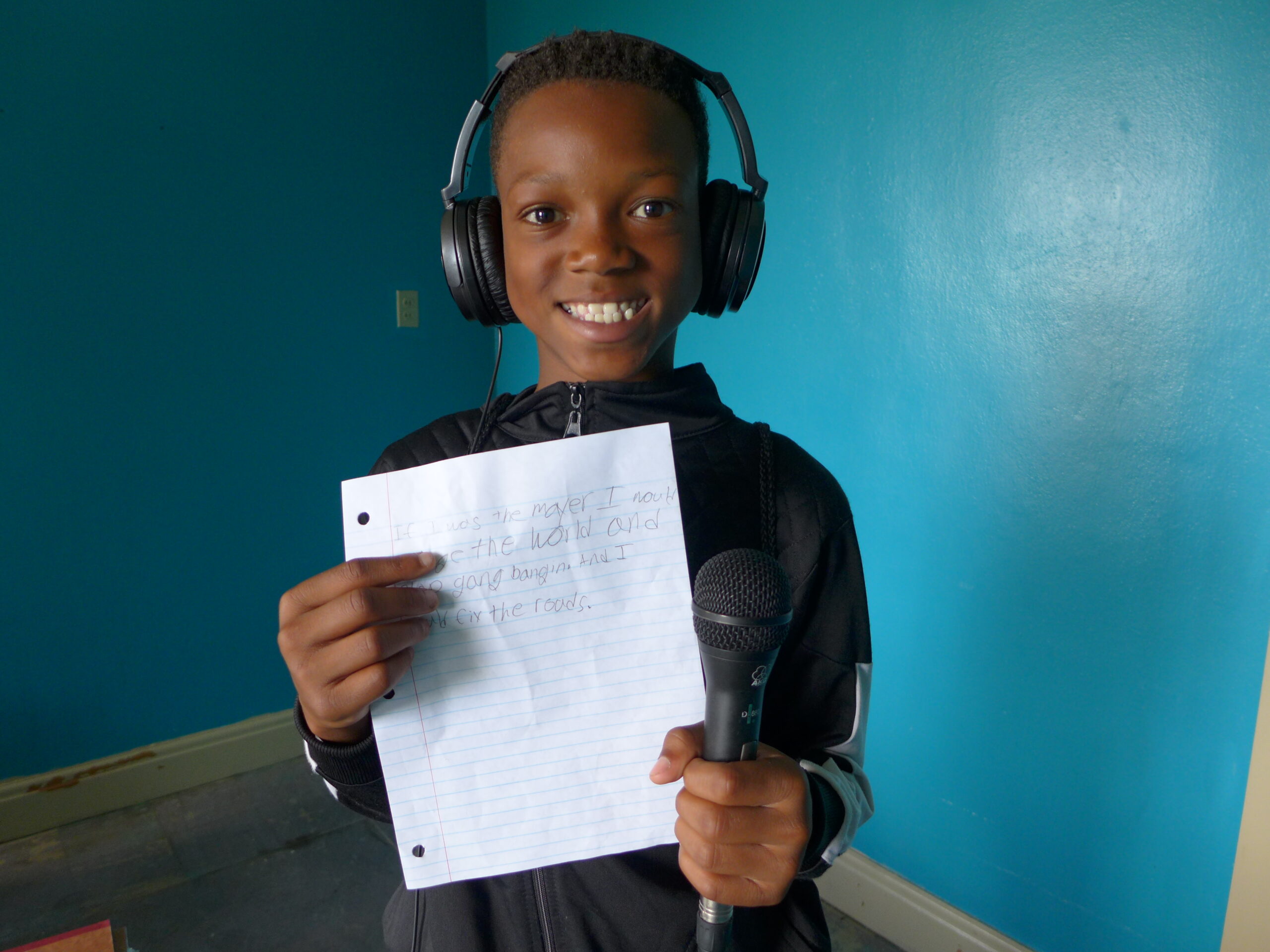 A youth wearing headphones proudly displaying a piece of paper