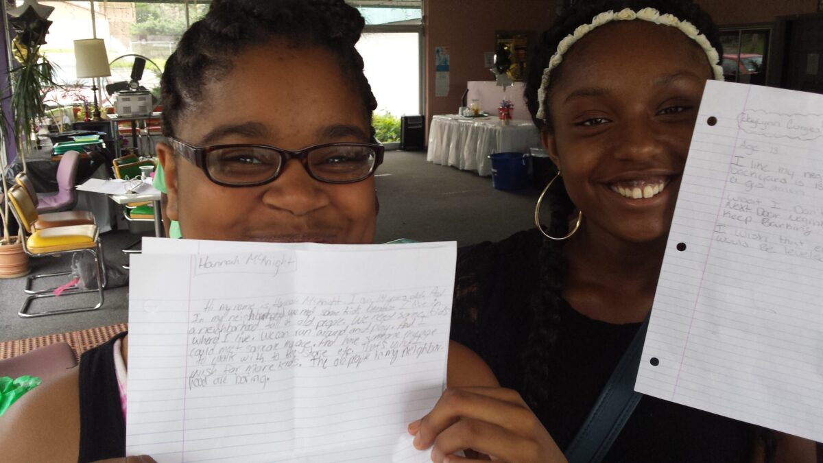 20150706_103808 Two youth holding up pieces of paper and smiling at the camera