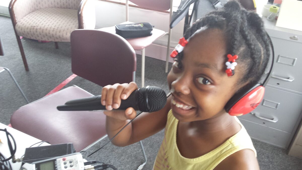 20150706_103814 A youth wearing headphones holding a microphone and smiling at the camera