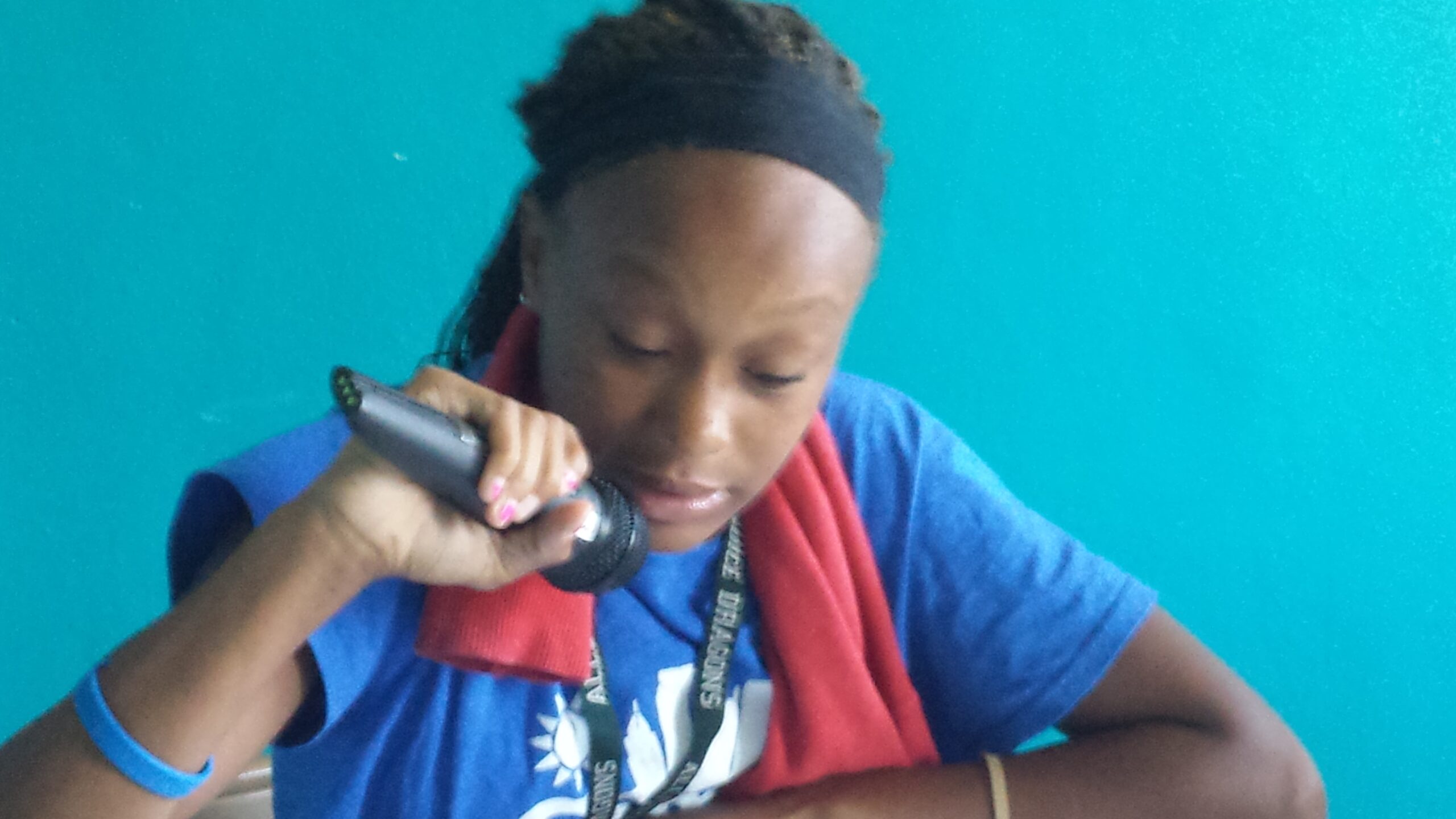 A youth holding and speaking into a microphone in front of a blue wall