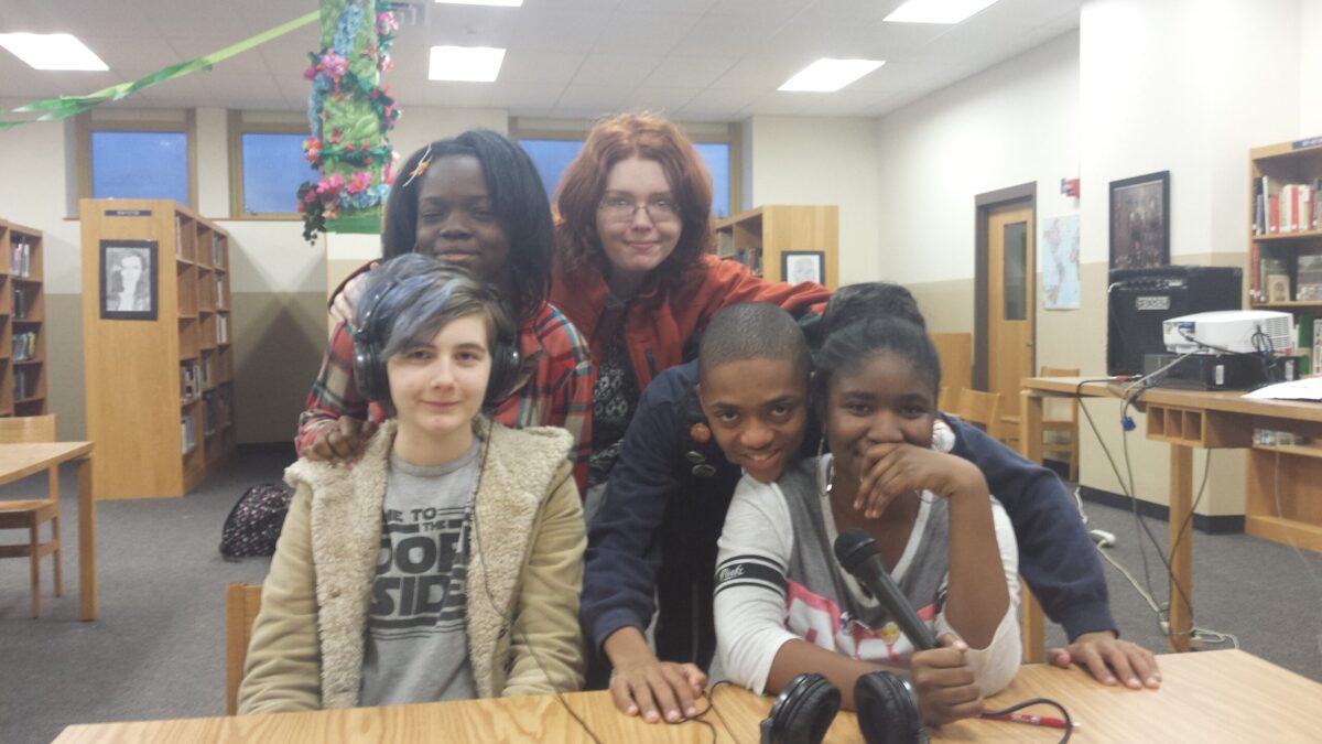 20151208_162851 Five teens smiling and posing behind a wooden table in a library