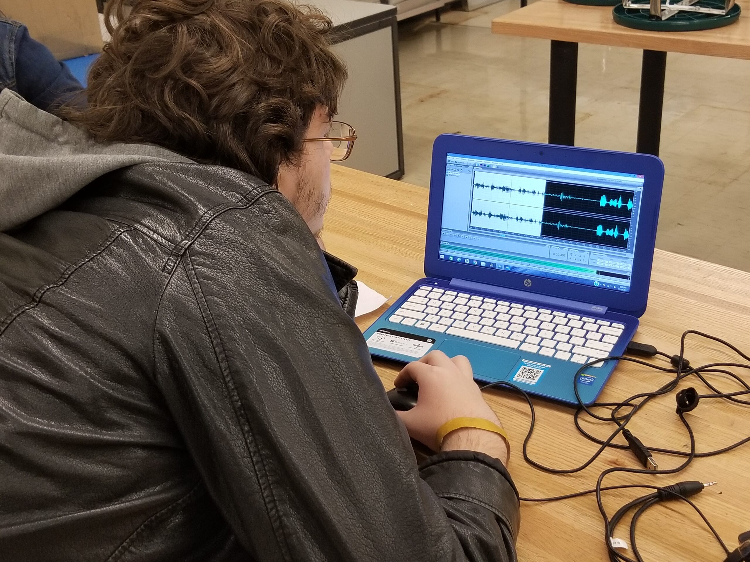 A teen looking at audio editing software on a blue laptop