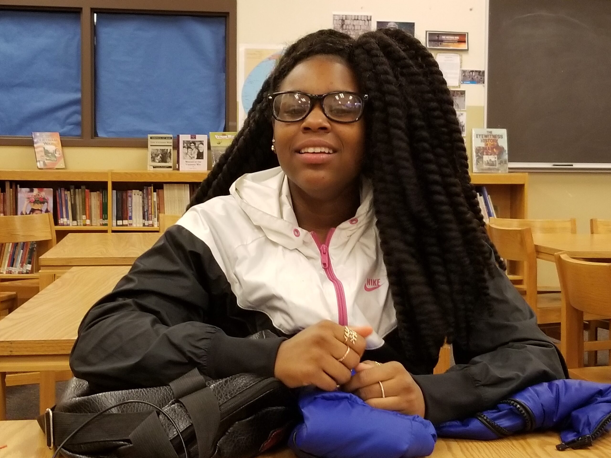 A youth smiling sitting in a classroom