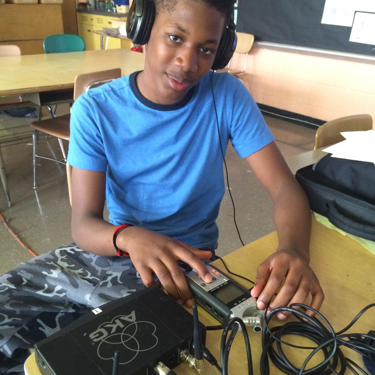IMG_1085 A youth wearing headphones interacting with a portable recorder on a classroom desk