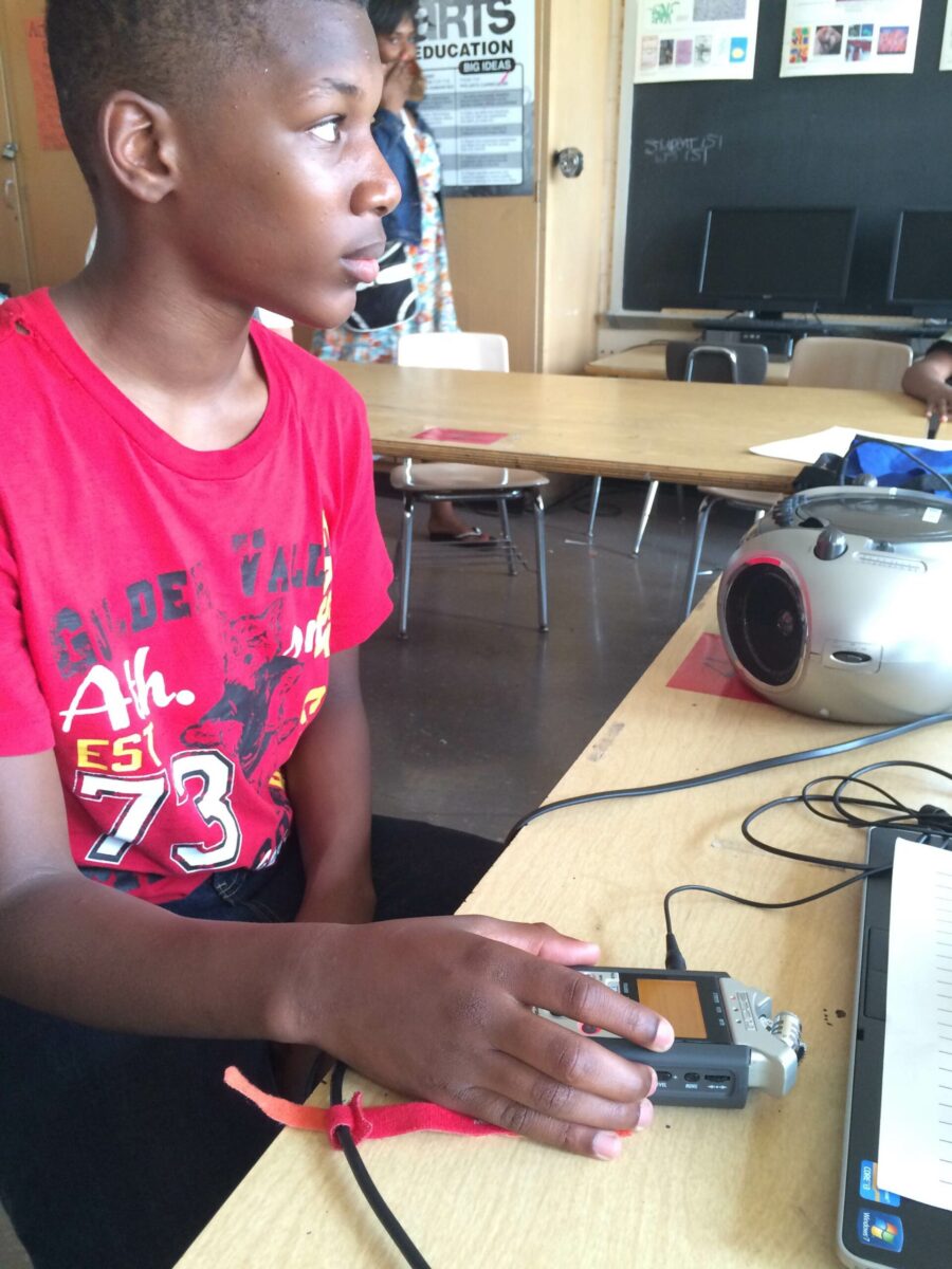 A youth interacting with a portable recorder in a classroom